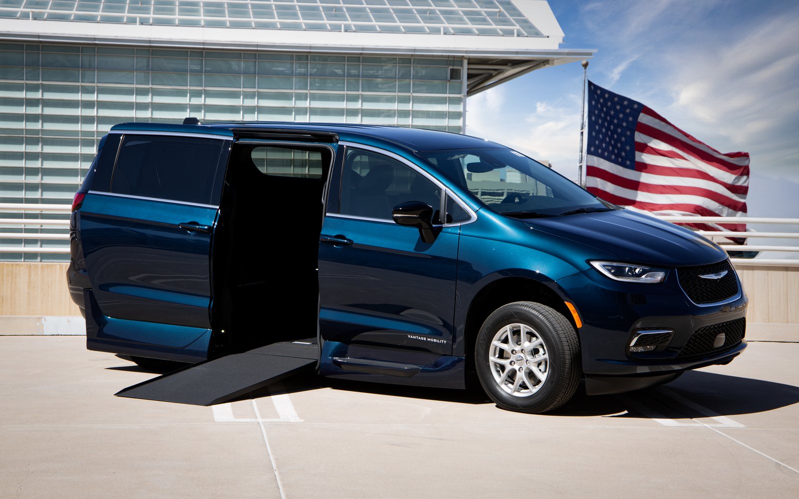A VMI Chrysler Pacifica Northstar with its side door open and the in-floor ramp extended to the ground, parked in an accessible bay.